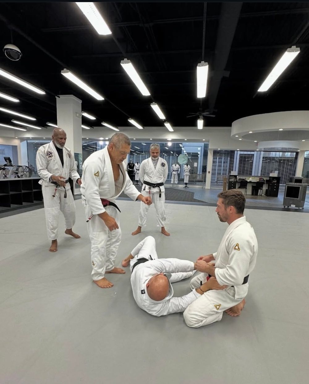 Rickson Gracie teaching a detail on the mat while James Driskill works the position
