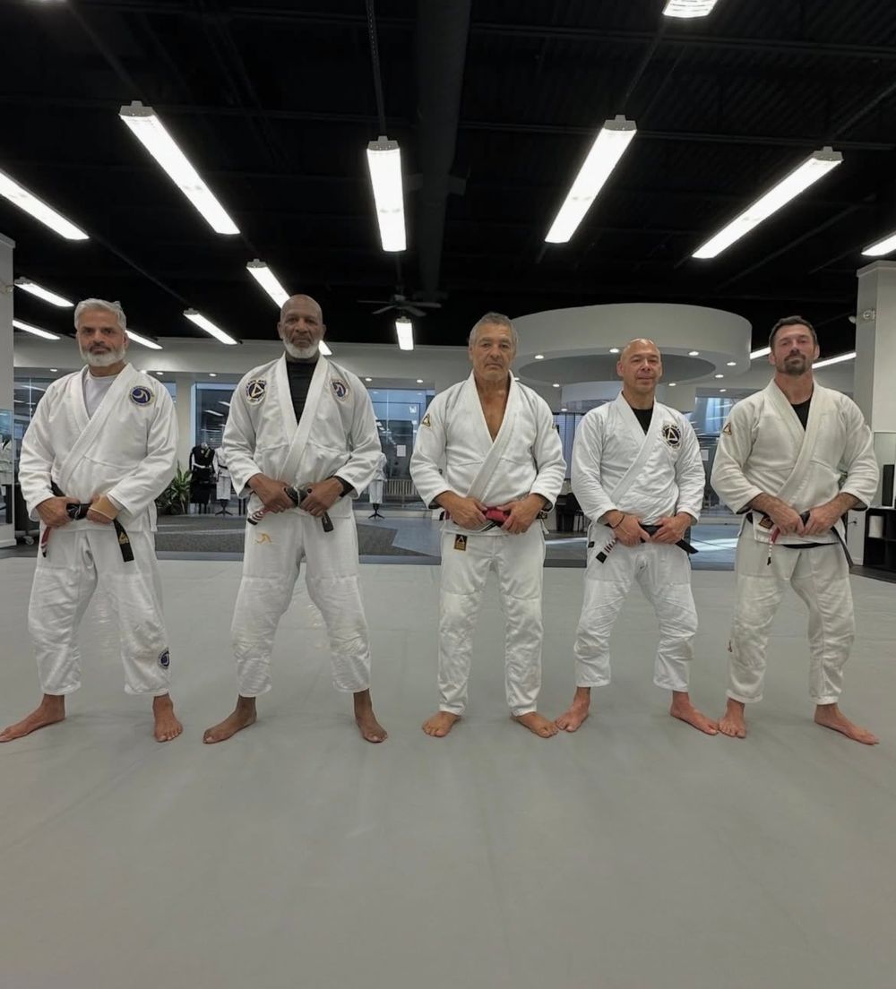 Rickson Gracie in his red belt with a line of black belts including James Driskill